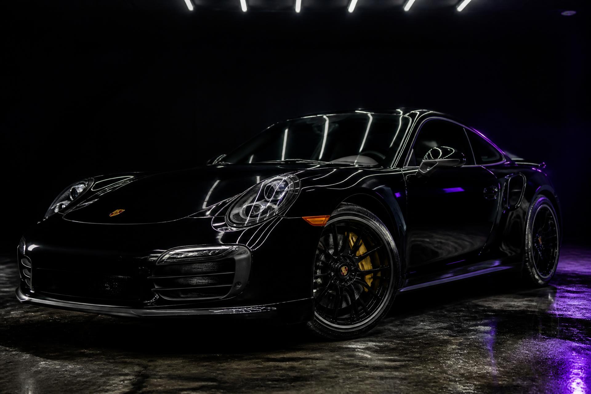 Freshly detailed black sports car under dramatic studio lighting